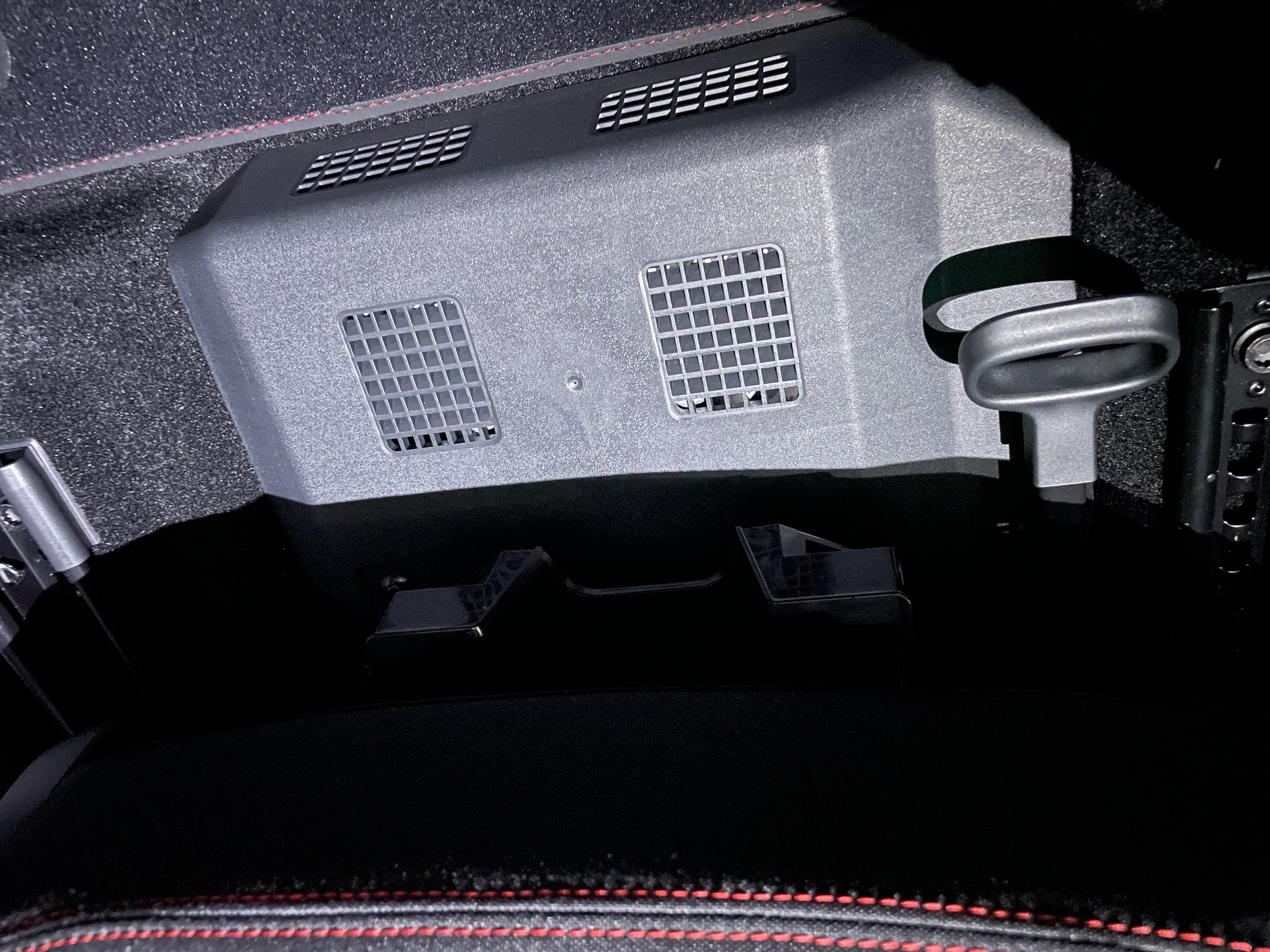 Metal cover under front passenger seat